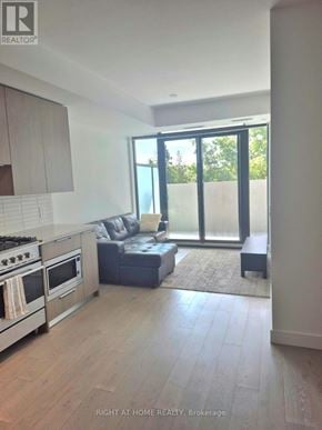 Toronto (Edenbridge-Humber Valley) condo for rent - A modern kitchen with a stove top oven and a grey sofa.
