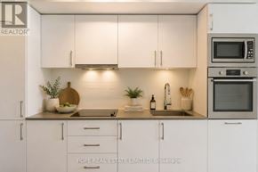 Toronto (Waterfront Communities) condo for rent - A kitchen with white cabinets and appliances, with a logo for "POPE REAL ESTATE LIMITED" in the corner.