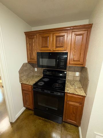 Temple triplex for rent - A kitchen with wooden cabinets and black appliances.