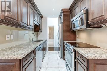 Toronto (Bayview Village) condo for rent - A kitchen with brown cabinets and granite countertops.