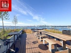 North Vancouver apartment for rent - A wooden deck with benches and a table overlooking a body of water.