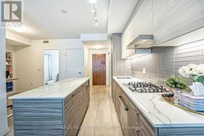 Toronto (Wychwood) condo for rent - A modern kitchen with a central island and a stove top oven.