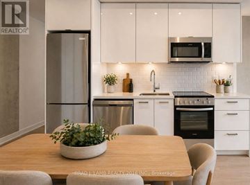 Toronto (Moss Park) condo for rent - A modern kitchen with a wooden table and chairs.