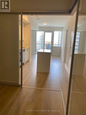 Toronto (Willowdale West) condo for rent - A hallway with a wooden floor and white walls leading to a balcony.