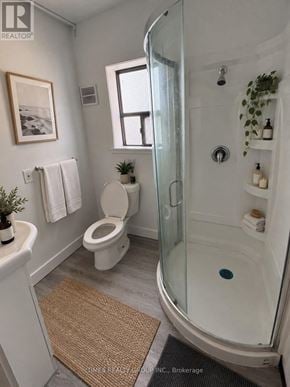 Toronto (Church-Yonge Corridor) multi-family for rent - A bathroom with a toilet, a glass shower stall, and a rug on the floor.