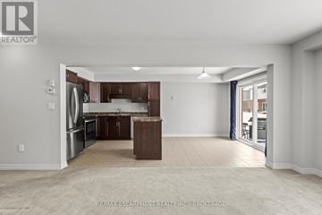 Thorold (Confederation Heights) townhouse for rent - A spacious kitchen with brown cabinets and a refrigerator.