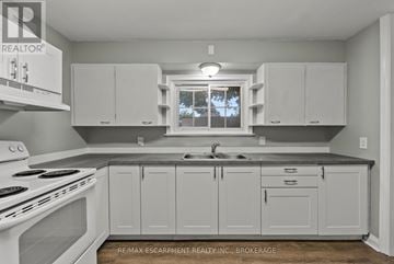 St. Catharines (Downtown) duplex for rent - A kitchen with white cabinets and a stove top oven.