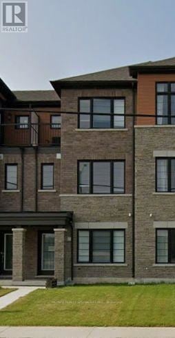 Thorold (Hurricane/Merrittville) townhouse for rent - A brown brick building with a green lawn in front.