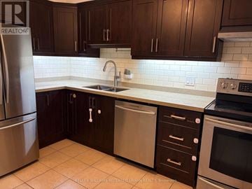 Toronto (Oakwood Village) triplex for rent - A kitchen with dark brown cabinets and a stainless steel refrigerator.
