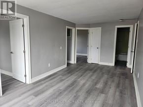 Welland (Welland Downtown) multi-family for rent - A room with grey walls and wooden flooring with a white door on the left.