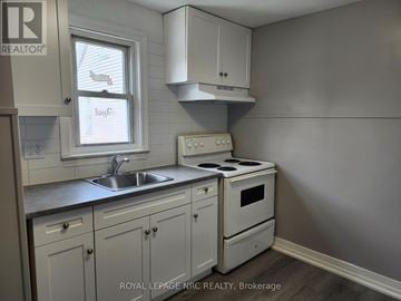 Welland (Welland Downtown) multi-family for rent - A kitchen with white cabinets and a stove top oven.