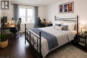 Stoney Creek townhouse for rent - A bedroom with a large bed, a desk with a chair, and a window with curtains.