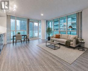 Toronto (Waterfront Communities) condo for rent - A modern living room with a large window and a view of a building.
