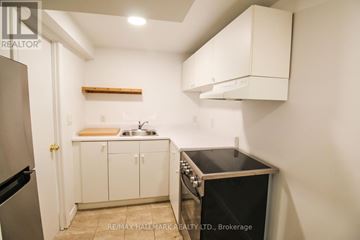 Toronto (South Riverdale) townhouse for rent - A small kitchen with a black oven and white cabinets.