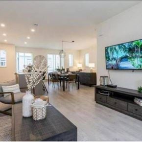Langley townhouse for rent - A modern living room with a television on the wall and a dining table with chairs.