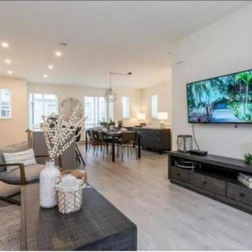 Langley townhouse for rent - A modern living room with a television on the wall and a dining table with chairs.