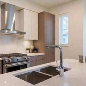 Langley townhouse for rent - A modern kitchen with a stainless steel range hood and a black and white countertop.