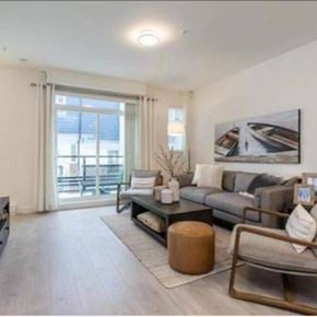 Langley townhouse for rent - A living room with a grey couch, a coffee table, and a large window with a view of a balcony.