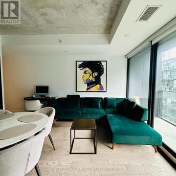 Toronto (Waterfront Communities) condo for rent - A living room with a green couch and a painting of a woman on the wall.