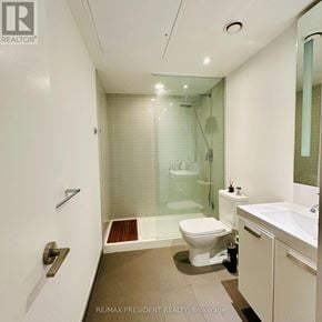 Toronto (Waterfront Communities) condo for rent - A white toilet is in a bathroom with a glass shower.