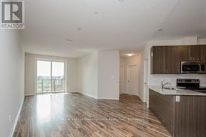 Milton (Sc Scott) condo for rent - A spacious living room with wood flooring and a kitchen area with white appliances.