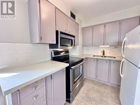 St. Catharines (Glendale/Glenridge) condo for rent - A kitchen with pink cabinets and a white fridge.