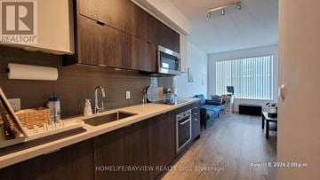 Toronto (Willowdale East) condo for rent - A kitchen with wooden cabinets and a countertop with a sink and microwave.
