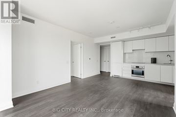 Toronto (Thorncliffe Park) condo for rent - A spacious kitchen with white cabinets and a wooden floor.