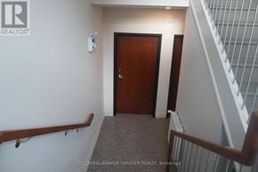 Ottawa apartment for rent - A hallway with a wooden door and a staircase with white railings.