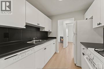 Windsor condo for rent - A kitchen with white cabinets and black countertops.