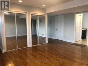 Amaranth apartment for rent - A room with wooden floors and white walls, with a glass door leading to another room.