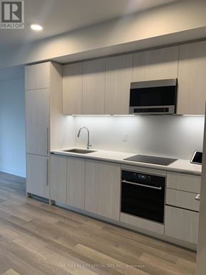 Toronto (Annex) condo for rent - A modern kitchen with white cabinets and a wooden floor.
