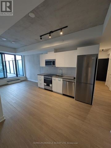 Toronto (Moss Park) condo for rent - A modern kitchen with wooden floors and stainless steel appliances.