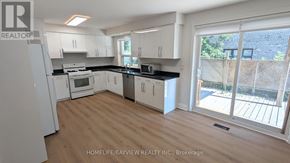 Richmond Hill (Mill Pond) apartment for rent - A kitchen with white appliances and cabinets with a sliding glass door leading to a backyard.
