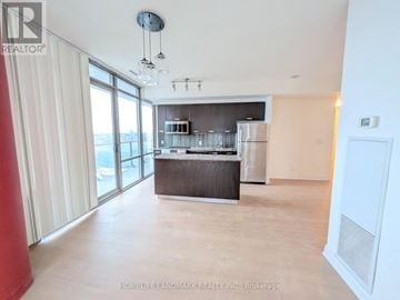 Toronto (Bay Street Corridor) condo for rent - A spacious kitchen with a refrigerator, sink, and stove is visible in the image.
