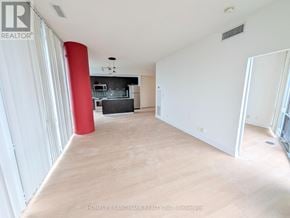 Toronto (Bay Street Corridor) condo for rent - A large, empty room with a red column and wooden flooring.
