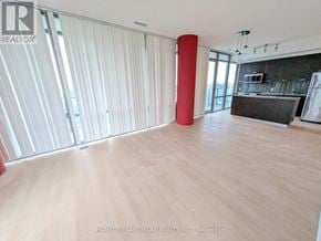 Toronto (Bay Street Corridor) condo for rent - A large, empty room with wooden floors and a red column.