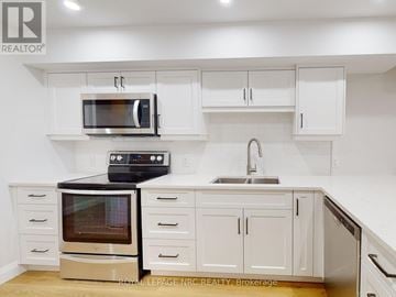 St. Catharines (Oakdale) apartment for rent - A white kitchen with a black microwave and oven.
