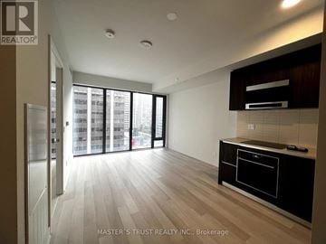 Toronto (Annex) condo for rent - A spacious kitchen with a refrigerator, oven, and a dining table with chairs.