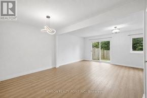 Hamilton (Gilkson) townhouse for rent - A room with wooden flooring and white walls, with a window showing greenery outside.