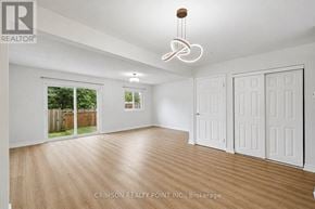Hamilton (Gilkson) townhouse for rent - A room with white walls and wooden flooring, with a large window and a sliding glass door.