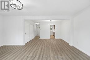 Hamilton (Gilkson) townhouse for rent - A large empty room with a light fixture on the ceiling and a brokerage logo on the wall.