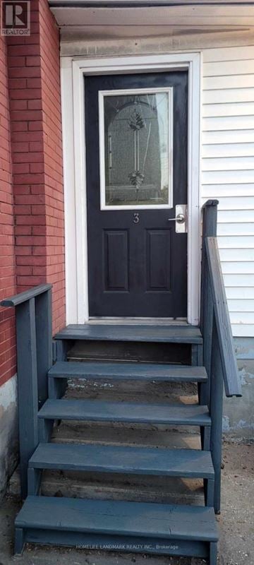 Oshawa (Central) triplex for rent - A black door with a glass window is on a red brick wall.