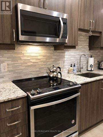 Richmond Hill (Langstaff) condo for rent - A modern kitchen with a stove top oven and microwave above it.