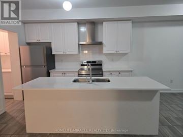 Barrie (Innis-Shore) townhouse for rent - A kitchen with white cabinets and a stainless steel refrigerator.