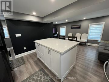 Brampton (Queen Street Corridor) apartment for rent - A modern kitchen with white cabinets and a black wall.