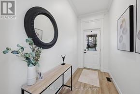 London East (East M) apartment for rent - A hallway with a white door, a mirror, and a table with a vase and plant on it.