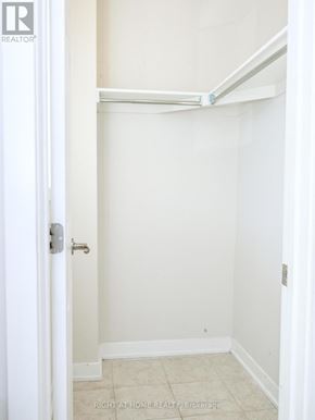 Ottawa townhouse for rent - A white door with a silver handle is open to a small, empty room with white walls and a tiled floor.