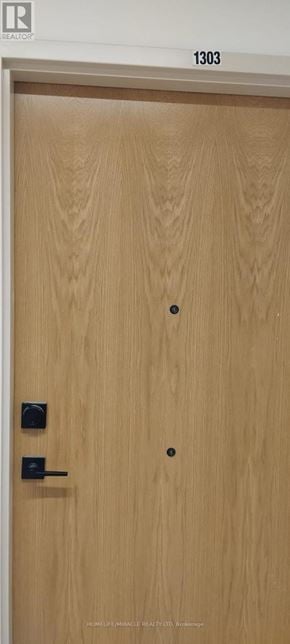 Brantford condo for rent - A wooden door with a black handle and a number 1303 above it.