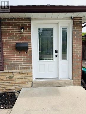Cambridge apartment for rent - A white door with a glass panel and sidelights is set in a brick wall.